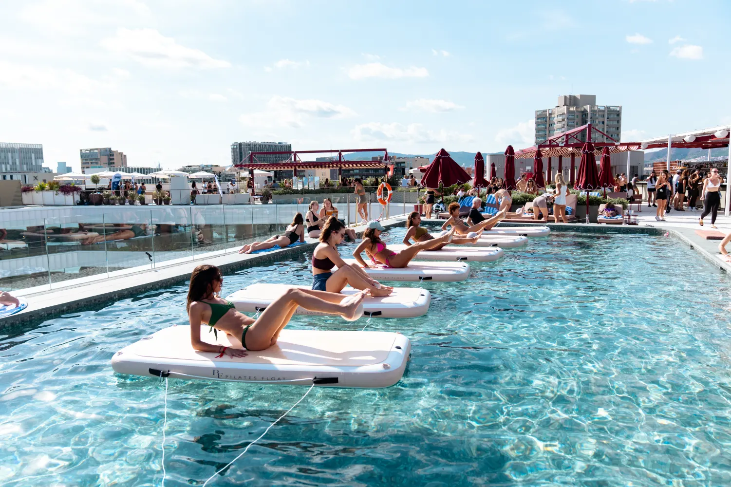 Guests on floating boards during a rooftop pool session